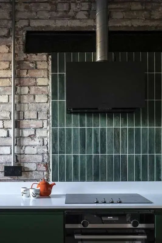 Industrial style kitchen showing white ceramic worktops and green ceramic tiles for splashback