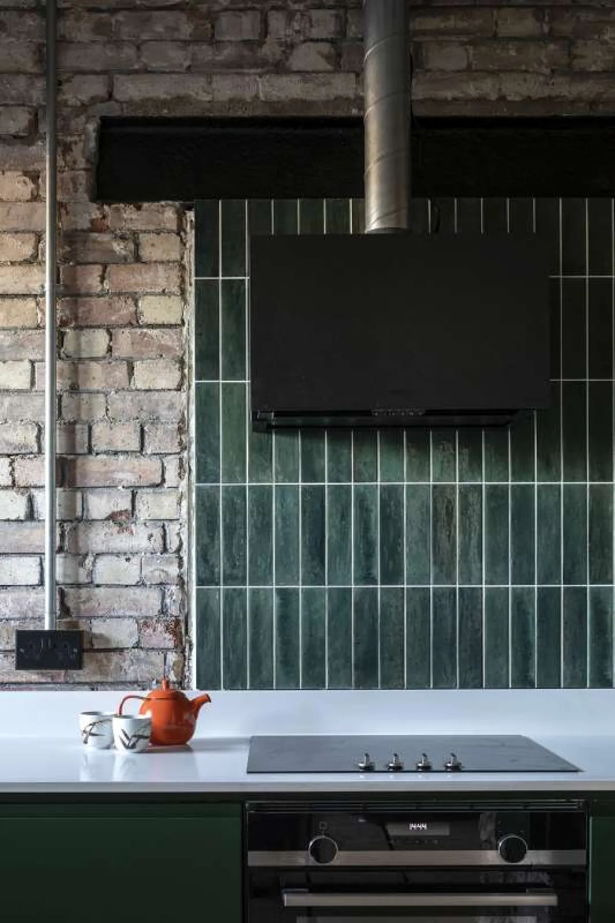 Industrial style kitchen showing white ceramic worktops and green ceramic tiles for splashback