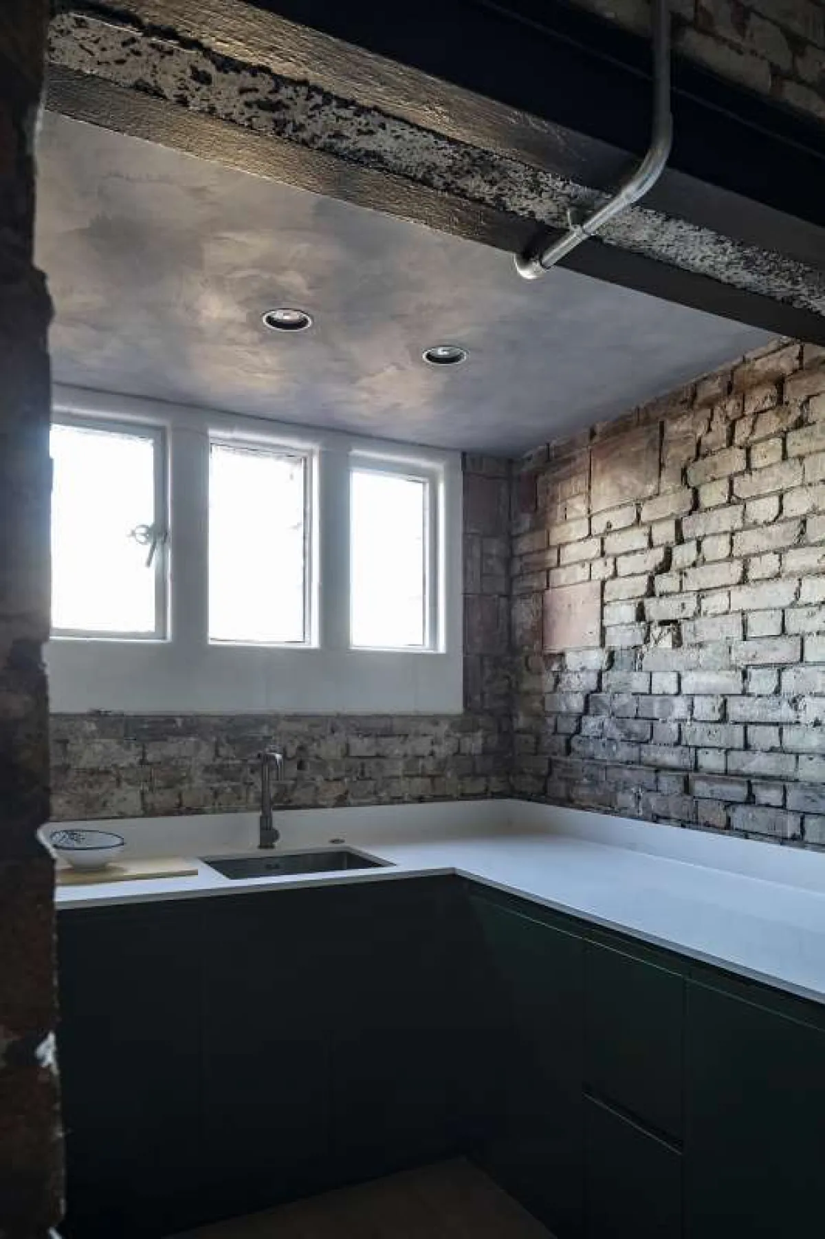 Industrial style kitchen showing white polished ceramic worktop and undermounted sink